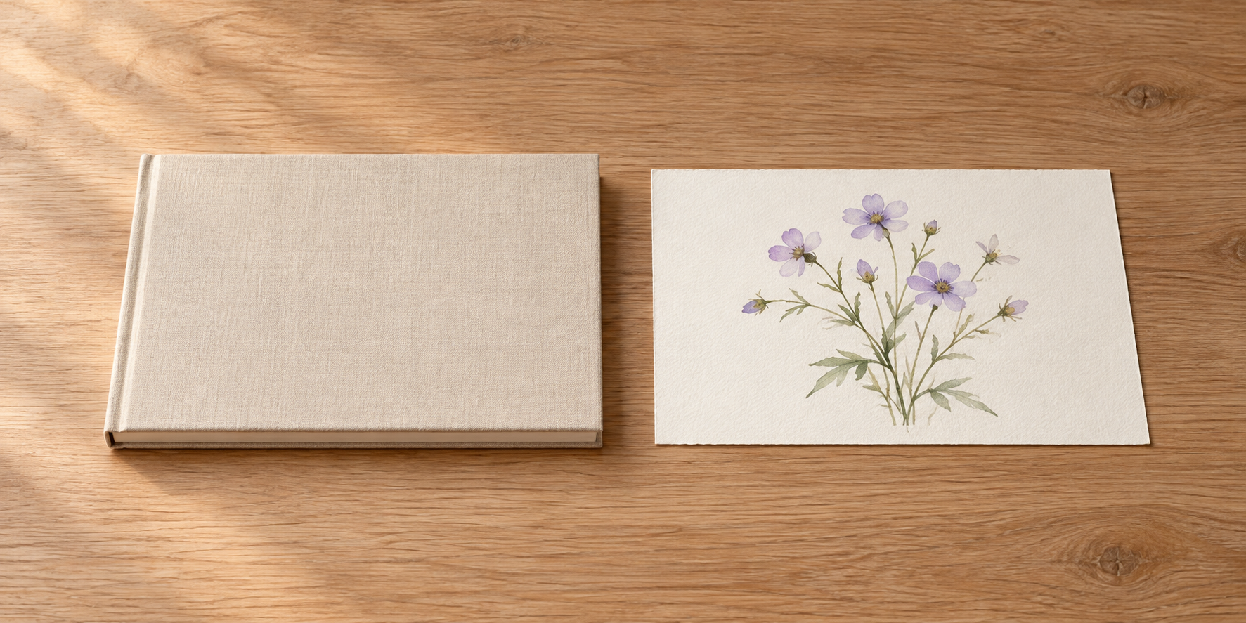 閉じた無地のノートと紫の小さな花を描いた紙を、木の机に離して並べている。